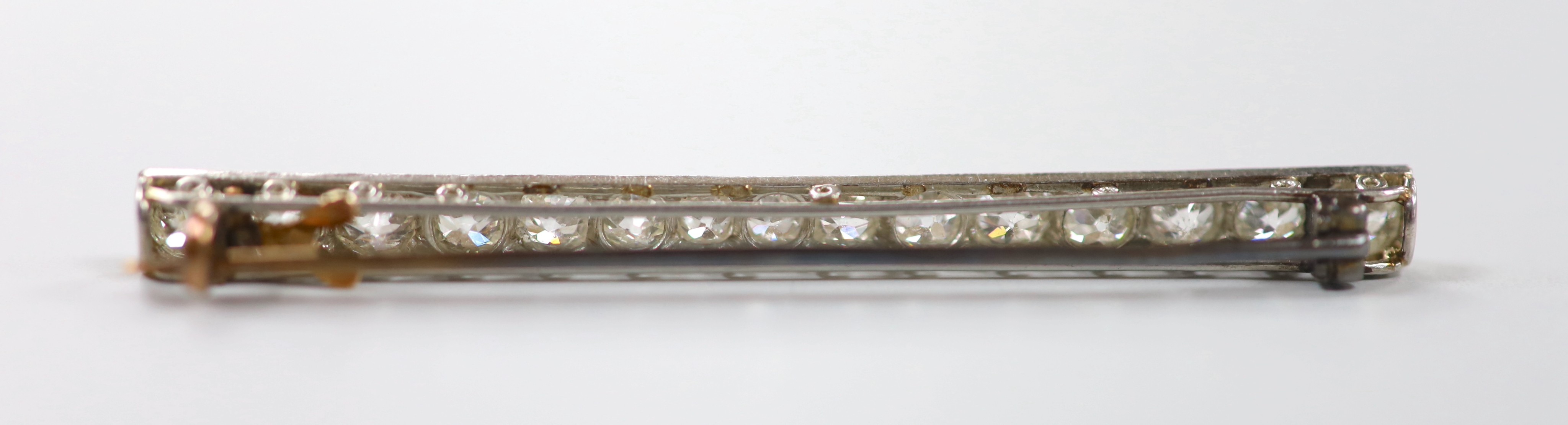 A 1920's white metal and millegrain set fifteen stone diamond bar brooch, 55mm, gross weight 4.6 grams.